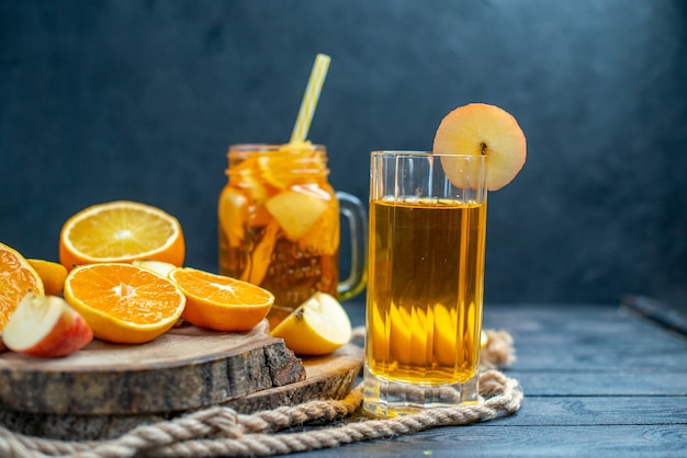 Front view cocktail cut oranges and apples on wood board on dark isolated background