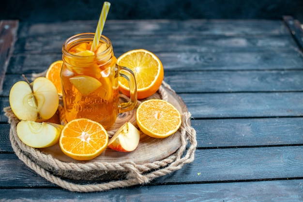 Front view cocktail cut oranges and apples on wood board on dark isolated background