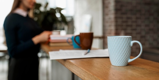 Free Photo front view of coffee mug on table counter with defocused woman