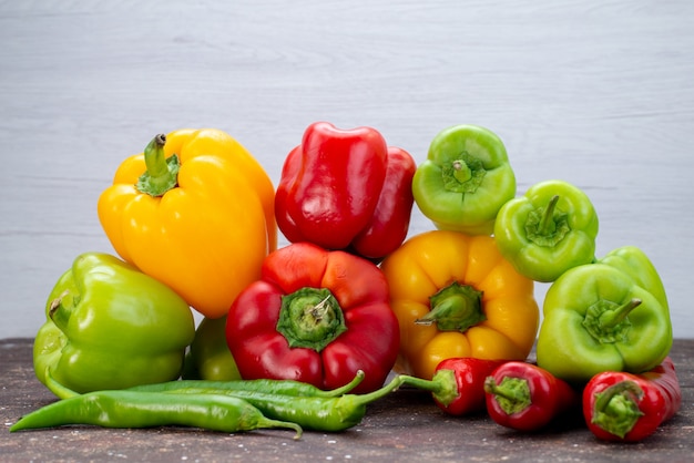 Front view colorful bell-peppers with peppers on the brown desk vegetable  color