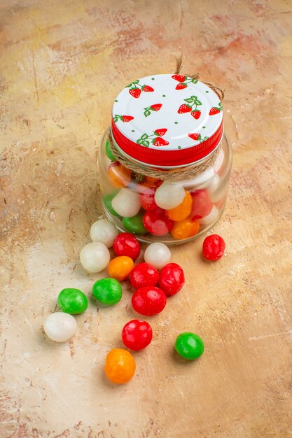 Front view colorful candies inside glass can on light floor