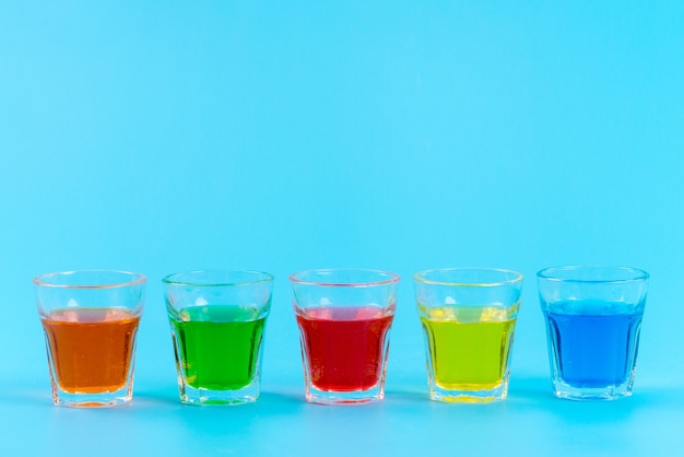 Free photo a front view colorful drinks inside glasses cooling on blue, juice fruit color ice