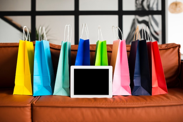 Free photo front view of colourful paper bags and tablet