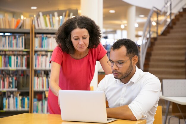 Front view of concentrated people looking at laptop together