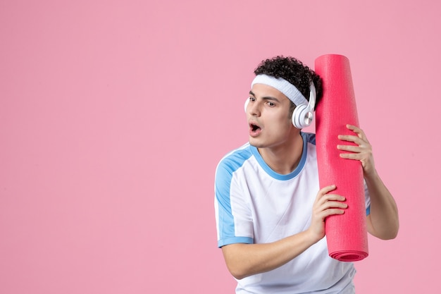 Free Photo front view concentrated young male in sport clothes with yoga mat