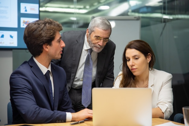 Front view of confident business team looking at laptop