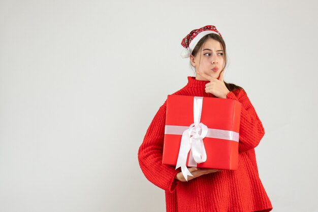 Front view confused girl with santa hat holding her xmas gift