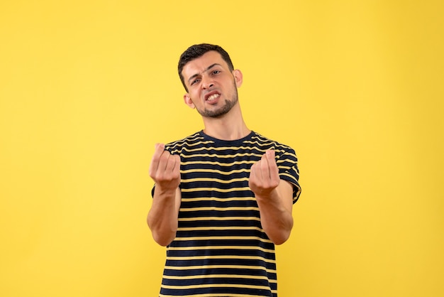 Front view confused young man in black and white striped t-shirt yellow isolated background