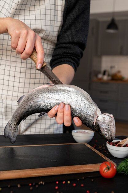 Front view cook cleaning fish in kitchen