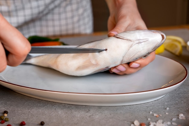 Front view cook cleaning fish in kitchen