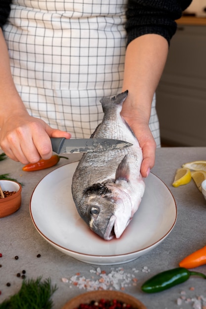 Free photo front view cook cleaning fish in kitchen