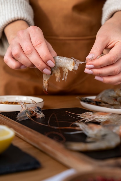 Front view cook cleaning shrimp in kitchen