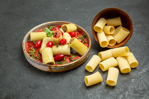 Front view cooked italian pasta delicious meal with tomato sauce on grey background dough pasta meat food sauce