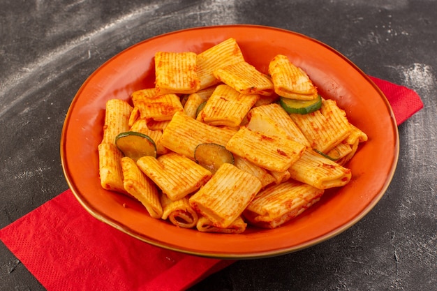 Free Photo a front view cooked italian pasta with tomato sauce and cucumber inside plate on the dark surface