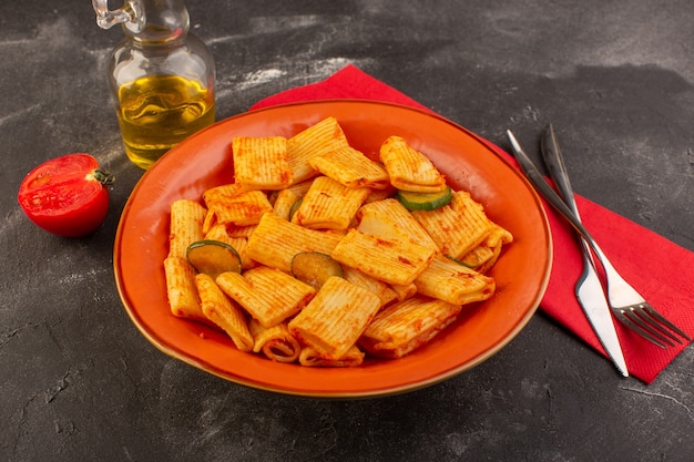 Free photo a front view cooked italian pasta with tomato sauce and cucumber inside plate on the dark surface