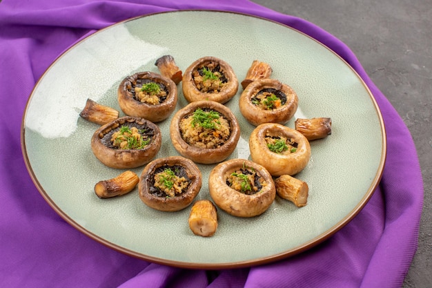 Free photo front view cooked mushrooms inside plate on a purple tissue dish meal mushrooms dinner cooking