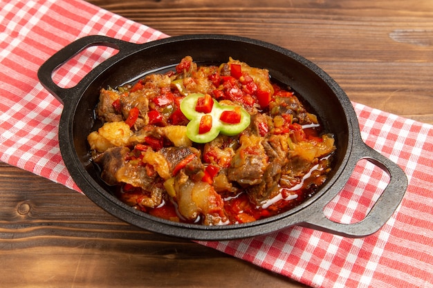 Front view cooked vegetable meal including vegetables and meat inside on brown desk