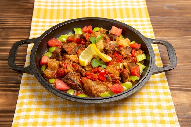 Front view cooked vegetable meal with meat and sliced bell peppers on brown desk