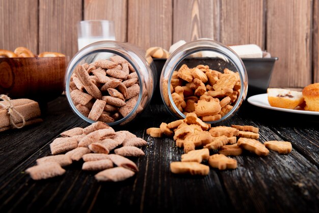 Front view cookies in a jar of cornflakes and corn sticks on a black wooden background