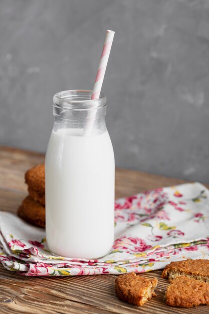 Front view cookies with milk bottle and straw on kitchen towel