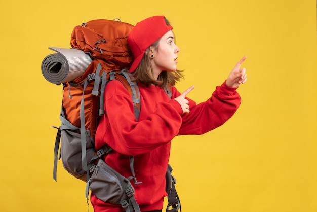 Front view cool female traveler with backpack pointing fingers right