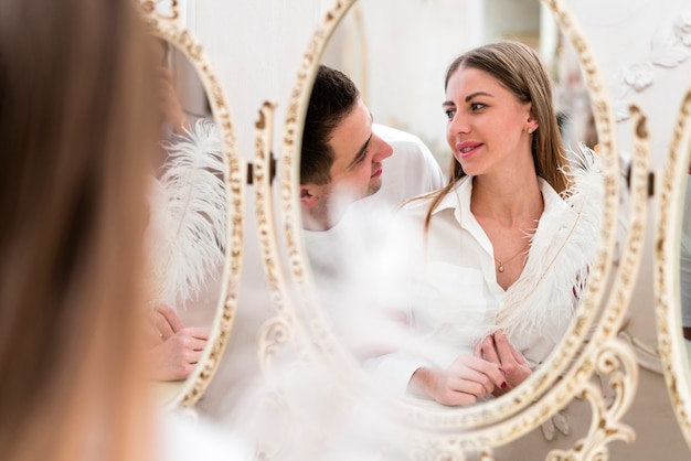 Front view of couple looking in the mirror with feather