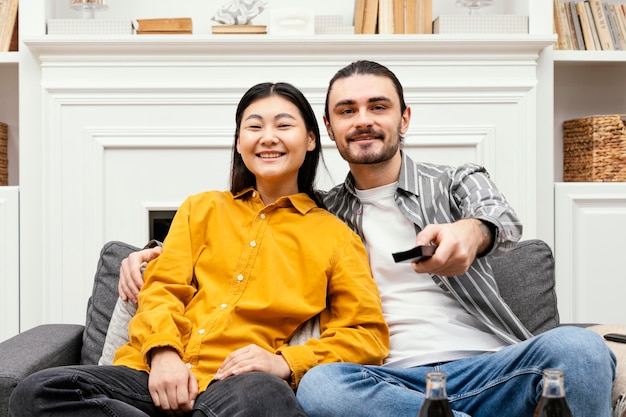 Front view couple sitting on the couch watching tv