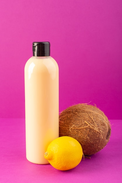 Free photo a front view cream colored bottle plastic shampoo can with black cap along with lemons and coconut isolated on the purple background cosmetics beauty hair