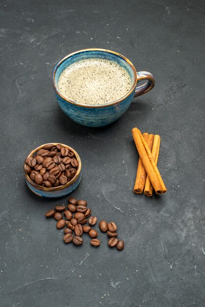 Front view a cup of coffee bowl with coffee bean seeds cinnamon sticks on dark isolated background