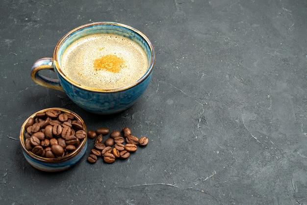 Free photo front view a cup of coffee bowl with coffee bean seeds on dark isolated background free place