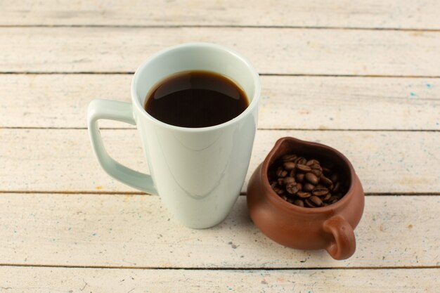 A front view cup of coffee in white cup with fresh brown coffee seeds on the light surfacedrink coffee caffeine