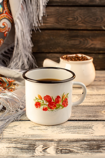 Free Photo front view of cup of coffee with brown coffee seeds on the wooden desk