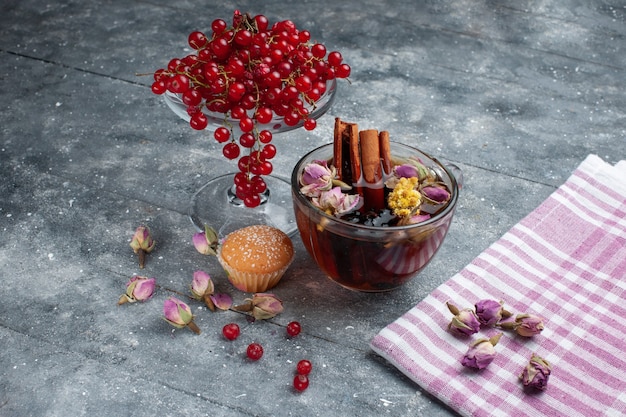 Front view cup of tea with cake cinnamon and fresh red cranberries on the grey desk sugar tea fruit berry