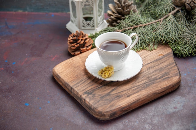 Front view cup of tea with cones on a dark space