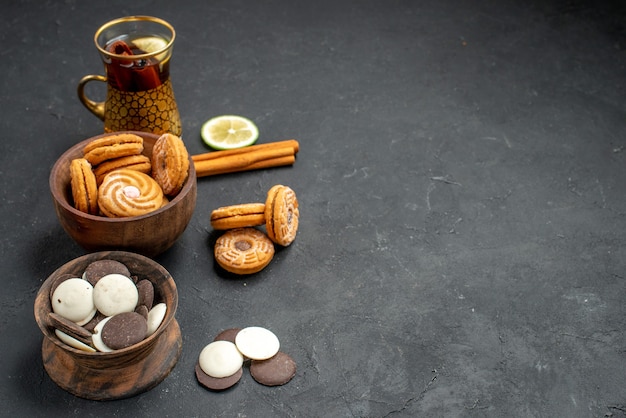 Free photo front view cup of tea with different cookies on gray background