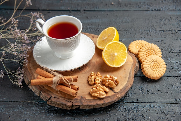 Front view cup of tea with lemon and cookies on dark background