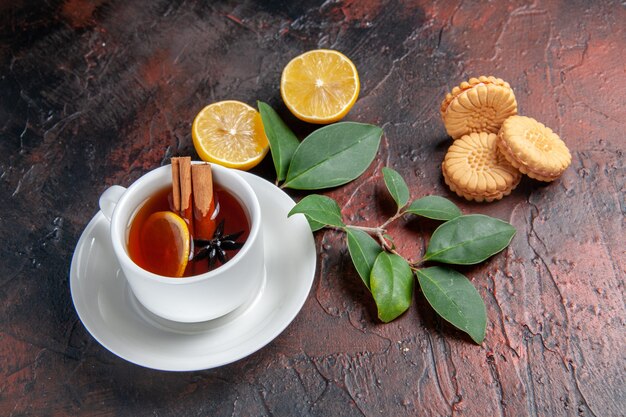 Front view cup of tea with lemon and cookies on dark background