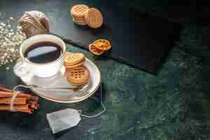 Free photo front view cup of tea with sweet biscuits on dark surface bread drink ceremony sweet breakfast morning photo sugar cake glass colors