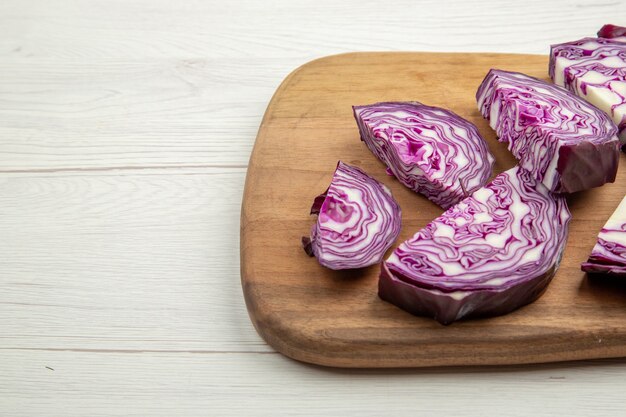 Front view cut red cabbages on wood cutting board on ground with free space