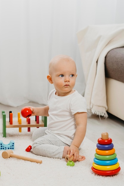 Front view of cute baby with toys at home