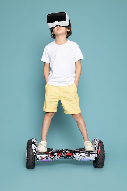 Free photo a front view cute boy playing vr on the segway in white t-shirt on the blue floor