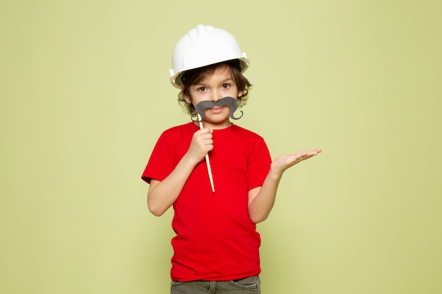 Free photo a front view cute boy in red t-shirt and white helmet on the stone colored space