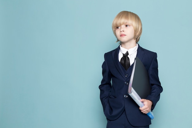 Free photo a front view cute business boy in blue classic suit holding black folder business work fashion