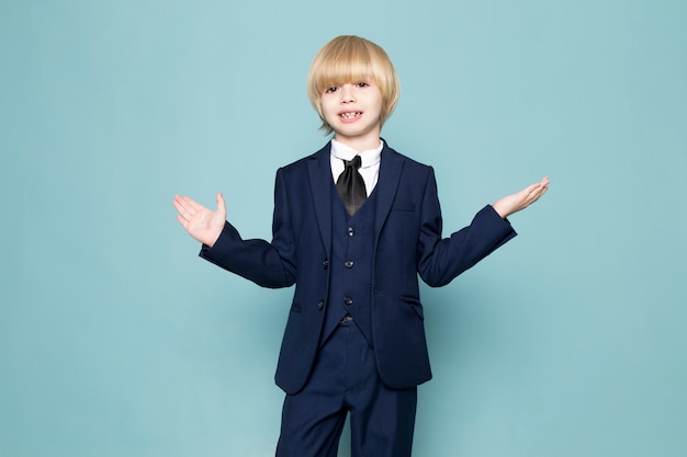 Free photo a front view cute business boy in blue classic suit posing business work fashion