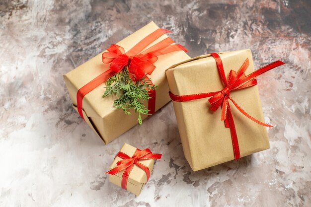 Front view cute christmas presents tied with red bows on light background