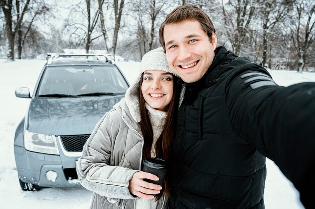 Front view of cute couple taking selfie while on a road trip