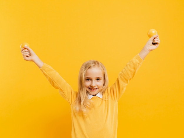 Free photo front view of cute girl posing while holding yellow light bulbs with copy space