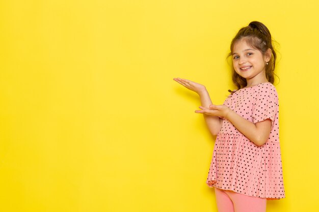 A front view cute little kid in pink dress smiling and posing