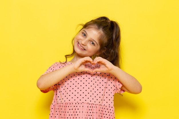 Free Photo a front view cute little kid in pink dress smiling and showing love sign