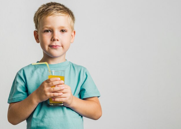 Front view cute young boy holding glass